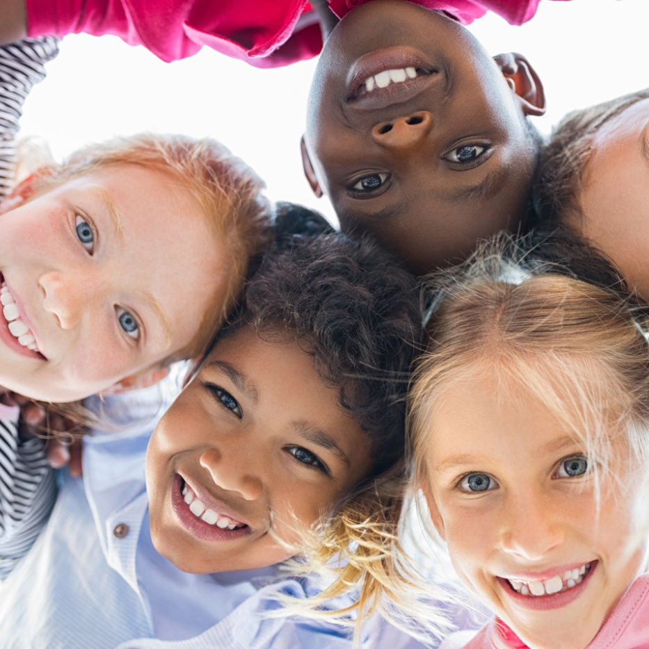 Kinder verschiedener Ethnien umarmen sich und lachen