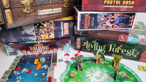 Eine Ansammlung von Brettspielboxen und Spielmaterialien verschiedener Designs und Themen.  Die Boxen sind übereinander gestapelt und auf einem weißen Untergrund angeordnet.  Auf einigen Boxen sind Bilder von Comicfiguren, Filmen und fantasievollen Motive